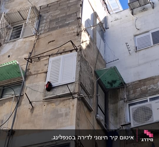בניין ישן עם חלונות ותריסים, חוטים חשמליים גלויים